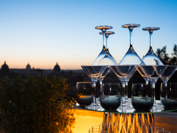 a Stack of martini and wine glasses on a table outside against a sunset